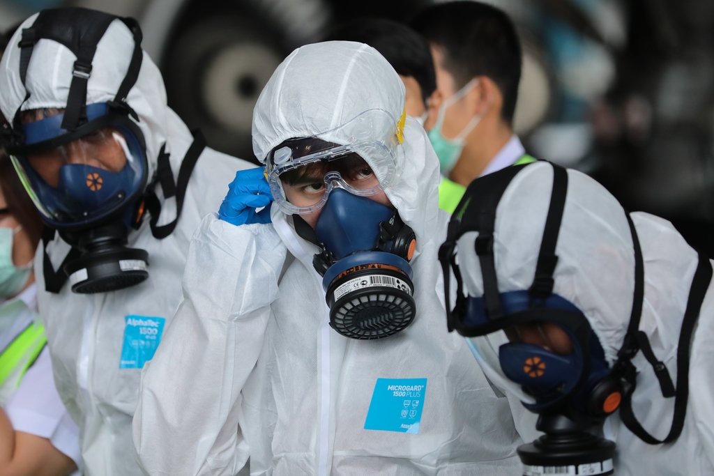 voor de Zekerheid Bemanningsleden van een Thais vliegtuig dragen beschermende kleding als passagiersstoelen in hun toestel worden gedesinfecteerd. Foto Getty